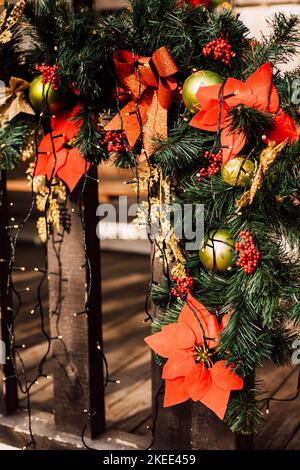 Weihnachtsschmuck und Christbaumzweige am Zaun auf der Straße Stockfoto