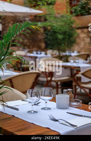 Ein Tisch in einem Restaurant im Freien mit traditionellen alten Terrakotta-Häusern in der Altstadt oder Vieille Ville in Villefranche sur Mer, Südfrankreich Stockfoto