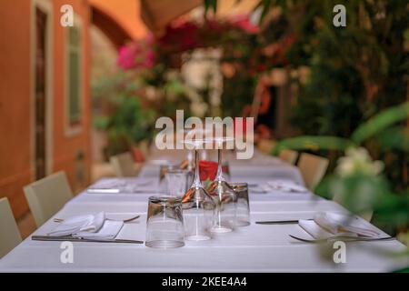 Ein Tisch in einem Restaurant im Freien mit traditionellen alten Terrakotta-Häusern in der Altstadt oder Vieille Ville in Villefranche sur Mer, Südfrankreich Stockfoto