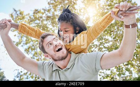 Vater, Adoptivkind und Mädchen, die draußen zum Spaß in einem Naturgarten fliegen und sich an der Vielfalt erfreuen. Mann, kleines weibliches Kind und Familie mit Kindern Stockfoto