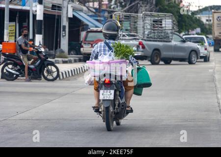 NAKHON NAYOK, THAILAND, JUNI 12 2022, Eine Frau trägt eine Last auf einem Motorrad Stockfoto