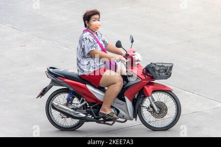 SAMUT PRAKAN, THAILAND, SEP 28 2022, Eine Frau mit Gesichtsmaske fährt ein Motorrad Stockfoto