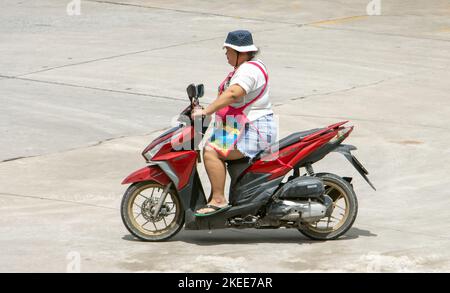 SAMUT PRAKAN, THAILAND, Okt 04 2022, Eine Frau mit Schürze fährt ein Motorrad Stockfoto