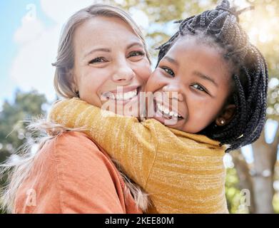 Mama, Kind und interracial umarmen sich im Park mit Lächeln, Bäumen und Sonnenschein im Sommer zum Kleben. Mutter, glückliches schwarzes Kind und Umarmung im Freien Stockfoto