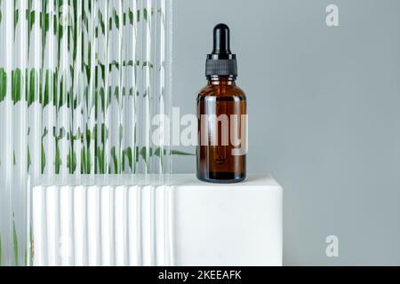 Beauty Face Öl in bernsteinfarbener Glasflasche auf einem Podium. Trendige Shoot von Kosmetik-Verpackung. Ätherisches Öl mit natürlichen Inhaltsstoffen. Grausamfreie c Stockfoto