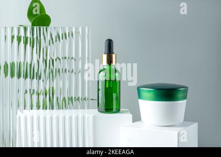 Anti-Aging Kollagen Gesichts-Serum in grüner Glasflasche und Gesichtscreme auf weißem Podium mit Kopierraum. Natural Organic Cosmetic Beauty Konzept. Stockfoto