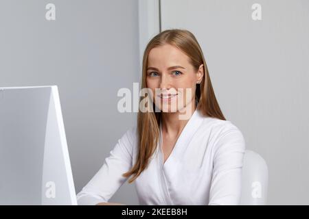 Lächelnde junge Ärztin, die bei der Konsultation mit ihrem Computer arbeitet Stockfoto