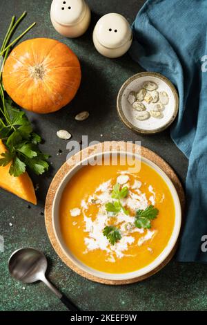 Vegetarische Kürbis- und Karottencremesuppe mit Creme und Kürbiskernen auf einer Steinplatte. Comfort Food, Herbst und Winter gesundes Slow Food Konzept. Vi Stockfoto