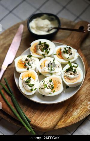 Gekochte Eierhälften mit Mayonnaise und grünen Zwiebeln. Stockfoto