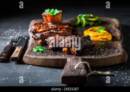 Köstliche und aromatisch geröstete Rippchen mit Gemüse und Sesam. Rippchen mit Kartoffelpüree als Fusion Cuisine. Stockfoto