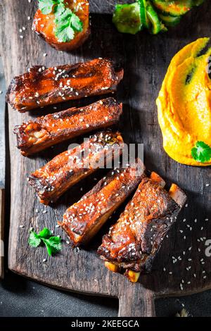 Scharf und würzig geröstete Rippchen mit Gemüse und Sesam. Rippchen mit Kartoffelpüree als Fusion Cuisine. Stockfoto
