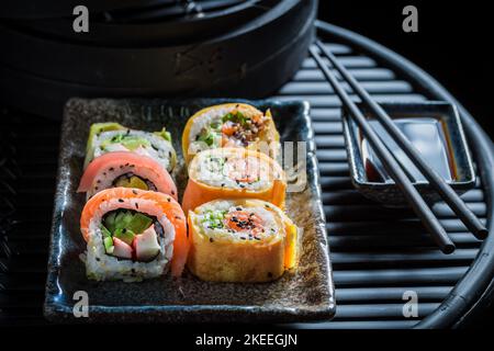 Köstliches und gesundes Sushi-Set auf schwarzem Schieferstein. Als klassische japanische Küche. Stockfoto