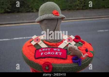 Leigh on Sea, Großbritannien. November 2022. Dekorative Häkelhülle über einem öffentlichen Postkasten in Leigh-on-Sea zum Gedenken an den Gedenktag. Mit einer Helm-Soldatenfigur, rotem Mohn, zwei Holzkreuzen, einem kleinen gestrickten Hund und einem zentralen Patch mit der Aufschrift „LEST WE FORGET“. Eine herzliche Hommage an gefallene Militärs durch kommunales Handwerk. Penelope Barritt/Alamy Live News Stockfoto