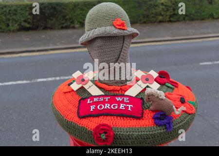 Leigh on Sea, Großbritannien. November 2022. Dekorative Häkelhülle über einem öffentlichen Postkasten in Leigh-on-Sea zum Gedenken an den Gedenktag. Mit einer Helm-Soldatenfigur, rotem Mohn, zwei Holzkreuzen, einem kleinen gestrickten Hund und einem zentralen Patch mit der Aufschrift „LEST WE FORGET“. Eine herzliche Hommage an gefallene Militärs durch kommunales Handwerk. Penelope Barritt/Alamy Live News Stockfoto