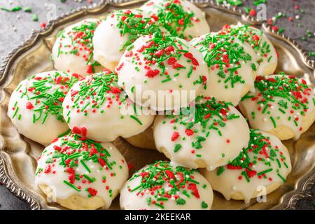 Italienische Weihnachtsplätzchen ein weicher und süßer Kuchen-ähnlicher Keks, der mit Glasur bedeckt ist und in der Nähe auf den Teller auf dem Tisch streut. Horizontal Stockfoto