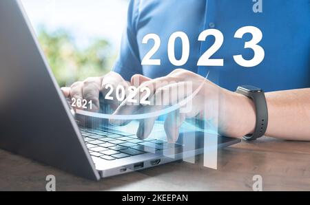 2023 Neujahr. Geschäftserfolg und Investitionswachstum in 2023 Jahren. Man Hand mit Laptop-Computer mit virtuellen Wachstumsdiagramm Diagramm, Aktien mar Stockfoto