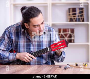 Die junge schöne Handwerker Reparatur Gitarre Stockfoto
