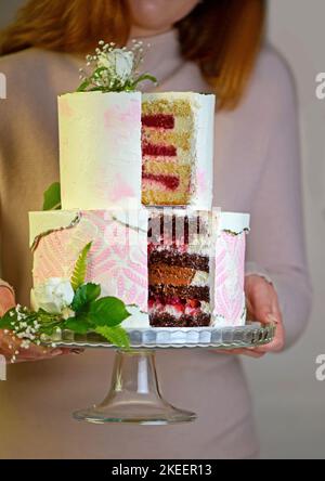 Hochzeitstorte mit frischen Blumen auf dunklem Hintergrund Stockfoto