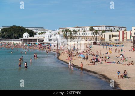 Sonnenanbeter an der Playa de la Caleta in der Nähe des Balneario de la Palma in Cádáiz, Andalusien, Spanien. Stockfoto