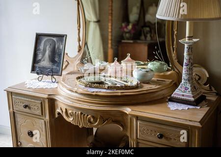 Antiker Kosmetikbereich und Spiegel mit einer Auswahl an Gläsern, Spiegel und Kammgarnitur sowie Hochzeitsfoto in der Umkleidekabine einer Braut im Panola Valley Gardens. Stockfoto