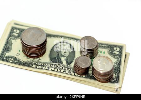 Stapel amerikanischer Dollar Geldscheine verschiedener Werte mit Stapeln amerikanischer Münzen von 1 Dollar, 50 Cent, Quartalen, 10 Cent Cent, Stockfoto