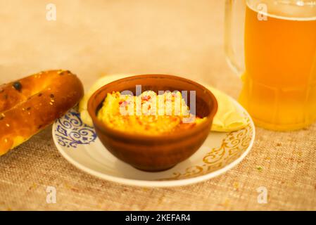 Hummus in ethnischer Schale und Bagel mit Sesam. Jüdische Snacks. Ein Glas Bier. Pint. Jüdisches Abendessen. Café. Restaurant. Orientalisches Muster auf einem Teller. Stockfoto