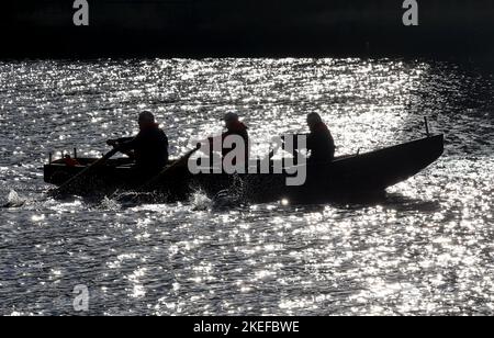 Eine Silhouette einer Currach, während die Crew entlang der Liffey in Dublin ruht. Bilddatum: Samstag, 12. November 2022. Stockfoto