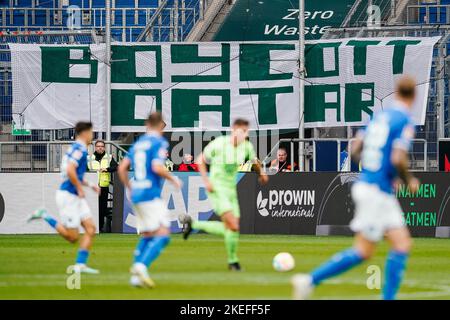 12. November 2022, Baden-Württemberg, Sinsheim: Fußball: Bundesliga, TSG 1899 Hoffenheim - VfL Wolfsburg, Matchday 15, PreZero Arena. Die Spieler kommen an einem Plakat im Fanblock von Wolfsburg mit der Aufschrift „Boykott Katar“ vorbei. Foto: Uwe Anspach/dpa - WICHTIGER HINWEIS: Gemäß den Anforderungen der DFL Deutsche Fußball Liga und des DFB Deutscher Fußball-Bund ist es untersagt, im Stadion und/oder des Spiels aufgenommene Fotos in Form von Sequenzbildern und/oder videoähnlichen Fotoserien zu verwenden oder zu verwenden. Stockfoto