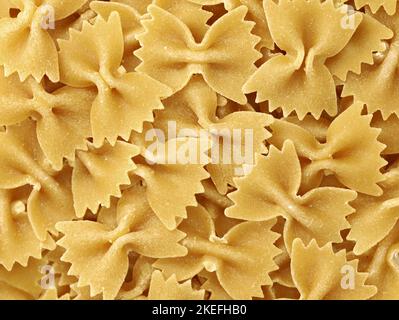 Nahaufnahme von trockenen, ungekochten italienischen Pasta-Farfalle, Hintergrund von Pasta in Schmetterlingsform Stockfoto