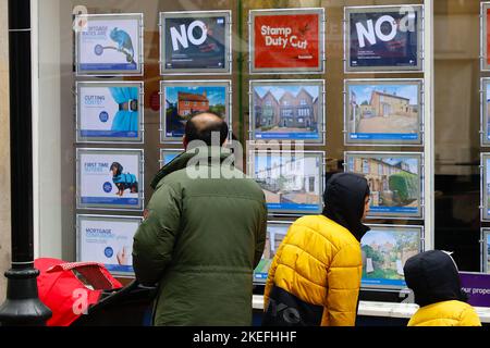 Ashford, Kent, Großbritannien. 12. November 2022. Einige Banken haben eine geringfügige Senkung der Hypothekenzinsen angekündigt. Ein Paar schaut durch das Fenster eines Immobilienmaklers in der Ashford High Street. Foto-Kredit: Paul Lawrenson /Alamy Live Nachrichten Stockfoto