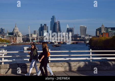 London, Großbritannien. 12.. November 2022. An einem ungewöhnlich warmen Novembertag, an dem die Temperaturen in der Hauptstadt steigen, laufen Frauen an der Waterloo Bridge vorbei an der Skyline der City of London. Kredit: Vuk Valcic/Alamy Live Nachrichten