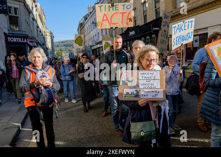 Bath, Großbritannien. 12.. November 2022. Die Demonstranten, die Plakate und Schilder zum Klimawandel tragen, sind abgebildet, während sie an einem protestmarsch zum Klimawandel durch das Zentrum von Bath teilnehmen. Der COP 27-Protest in Bath war Teil eines globalen Aktionstages, an dem Menschen heute weltweit auf die Straße gingen, um die Staats- und Regierungschefs der Welt dazu zu bewegen, beim Treffen ihrer Verhandlungsführer in Ägypten auf der COP 2022 der UN-Klimakonferenz zu handeln. Quelle: Lynchpics/Alamy Live News Stockfoto