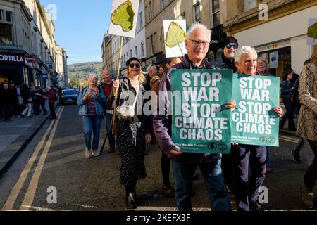 Bath, Großbritannien. 12.. November 2022. Die Demonstranten, die Plakate und Schilder zum Klimawandel tragen, sind abgebildet, während sie an einem protestmarsch zum Klimawandel durch das Zentrum von Bath teilnehmen. Der COP 27-Protest in Bath war Teil eines globalen Aktionstages, an dem Menschen heute weltweit auf die Straße gingen, um die Staats- und Regierungschefs der Welt dazu zu bewegen, beim Treffen ihrer Verhandlungsführer in Ägypten auf der COP 2022 der UN-Klimakonferenz zu handeln. Quelle: Lynchpics/Alamy Live News Stockfoto