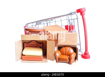 Miniatur-Lieferkisten mit winzigen Möbelfiguren in einem kleinen, auf weißem Hintergrund isolierten Einkaufswagen. Möbelgeschäft Werbebanner. Stockfoto