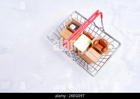 Miniatur-Kopien von wichtigen Einrichtungsgegenständen und kleinen Lieferkisten in einem Warenkorb, Draufsicht. Neues Wohnmobiliar-Konzept. Stockfoto