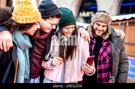 Gruppe von Millennial trendy Freunde zu Fuß im Stadtzentrum mit dem Handy - Tech Life Style Konzept mit glücklichen jungen Menschen auf Wintermode kleiden Stockfoto