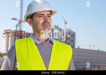 Professioneller Baumeister, der mit Notebook vor der Baustelle steht Stockfoto