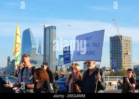 London, Großbritannien. 12.. November 2022. Demonstranten marschieren über die Waterloo Bridge mit Fahnen und Plakaten. Klimaaktivisten verschiedener Organisationen versammelten sich, nachdem ägyptische zivilgesellschaftliche Gruppen auf der Cop 27 zu weltweiten Protesten aufgerufen hatten, um die Ursachen der Klimakrise und Ungerechtigkeiten anzugehen und den Übergang zu erneuerbaren Energien zu fördern. Londoner Aktivisten hoben den Fall des inhaftierten Schriftstellers Alaa Abd El-Fattah und den Tod von Mahsa Amini und Chris Kaba in Polizeigewahrsam hervor. Kredit: Elfte Stunde Fotografie/Alamy Live Nachrichten Stockfoto