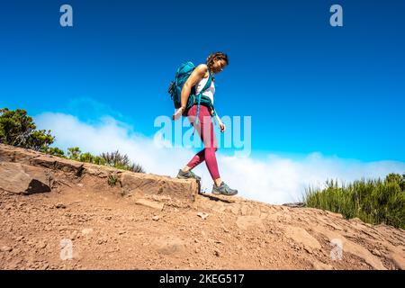 Beschreibung: Wanderer mit Rucksack eine Stufe entlang des Wanderweges auf Pico Ruivo hinunter. Verade do Pico Ruivo, Madeira, Portugal, Europa. Stockfoto