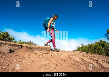 Beschreibung: Wanderer mit Rucksack eine Stufe entlang des Wanderweges auf Pico Ruivo hinunter. Verade do Pico Ruivo, Madeira, Portugal, Europa. Stockfoto