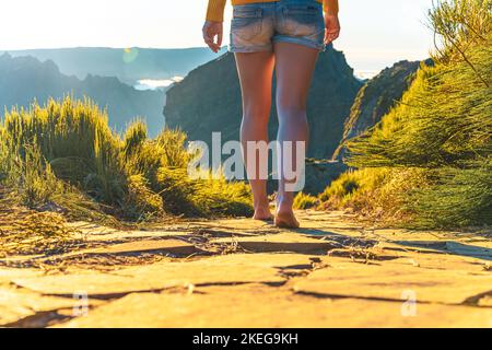 Beschreibung: Beine einer athletischen Frau, die barfuß in der Abendsonne auf dem Pico do Ariero auf einem super schönen Wanderweg läuft. Verade do Pico Ruivo, Stockfoto