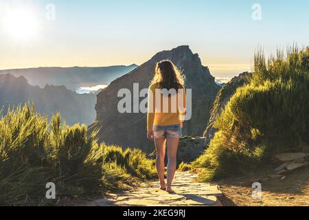 Beschreibung: Sportliche Frau, die barfuß in der Abendsonne auf dem Pico do Ariero auf einem super schönen Wanderweg läuft. Verade do Pico Ruivo, Madeira Stockfoto