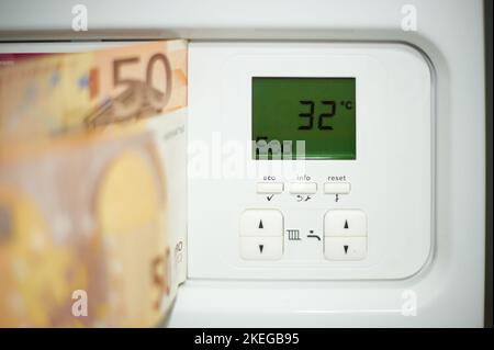 Euro-Rechnungen an der Tür des Heizkessels mit Ziffern der Temperatur des Thermostats. Stockfoto