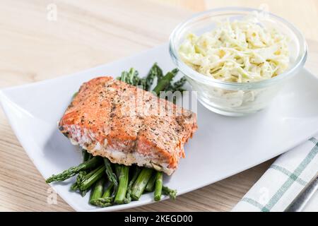 Eine Nahaufnahme eines Lachs auf Spargel, serviert auf einem weißen Teller Stockfoto