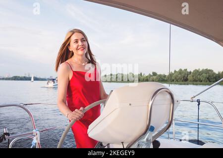 Hübsche Frau, die an einem sonnigen Sommertag am Fluss auf der Yacht posiert Stockfoto