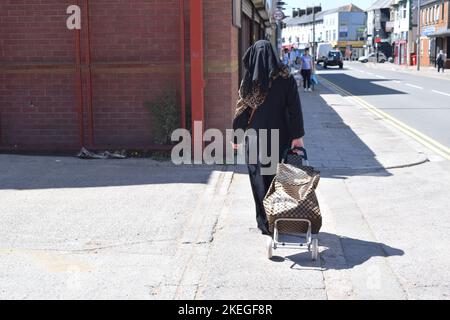 Muslimische Frauen kaufen an einem sonnigen Tag in der britischen Stadt ein. Stockfoto