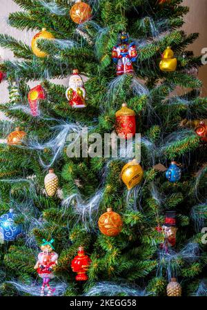 Zu Hause hängen Weihnachtsdekorationen und Neujahrsdekorationen am Weihnachtsbaum. Schöne Ornamente, helle festliche Kugeln auf dem Hintergrund von grünen Tannenzweigen. Thema o Stockfoto