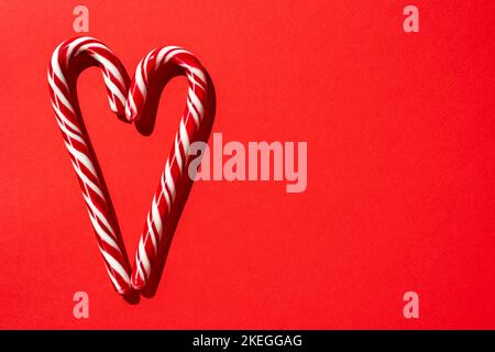 Valentinstag. Hintergrund der Feiertage. Herz aus Zuckerstöcken auf rotem Hintergrund Stockfoto