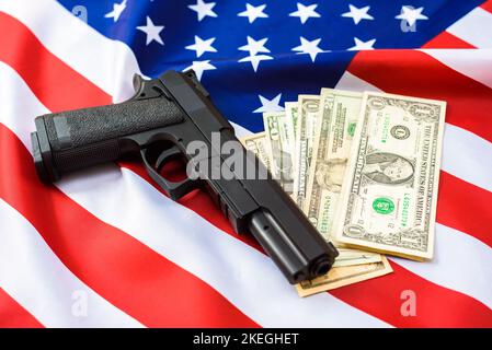 Gun über amerikanische Flagge mit Dollarscheinen um sie herum. Stockfoto