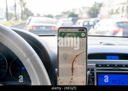 Algier. Routenstau in der Kartenanwendung, Smartphone-Bildschirm im Armaturenbrett des Fahrzeugs und Verkehrsstau auf der Außenseite der Bremsansicht von der Windschutzscheibe. Stockfoto